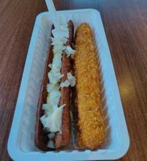 Een frikandel met uitjes en een tweede snack in een bakje